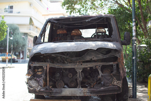 A burnt and damaged van parked at a street of the city.