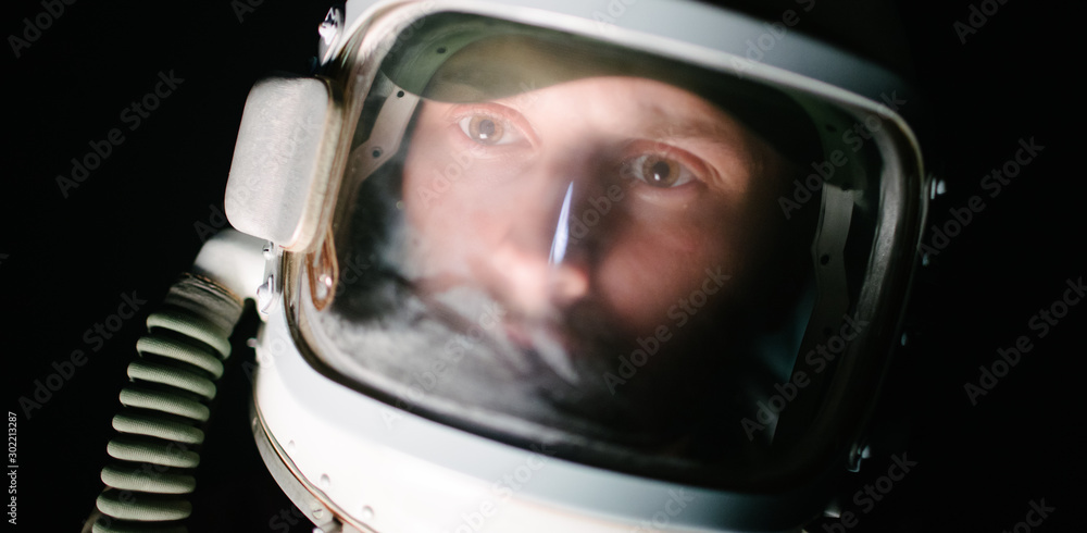 Astrounaut man in a helmet looking ahead exploring the earth in a dark Astrounaut man in a helmet looking ahead exploring the earth in a dark