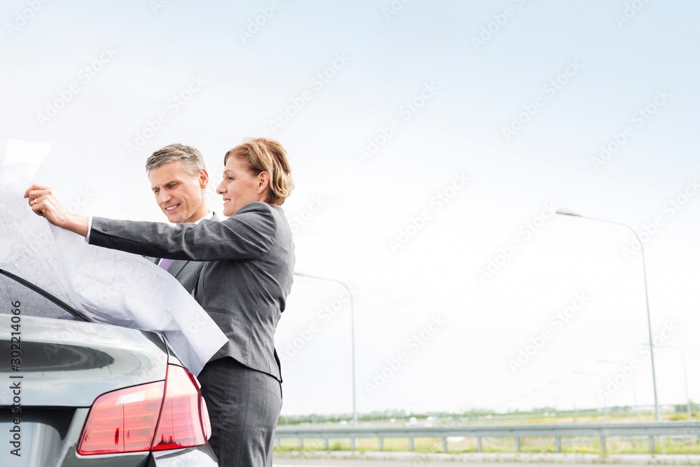 Business poeple looking at the map outside broken car