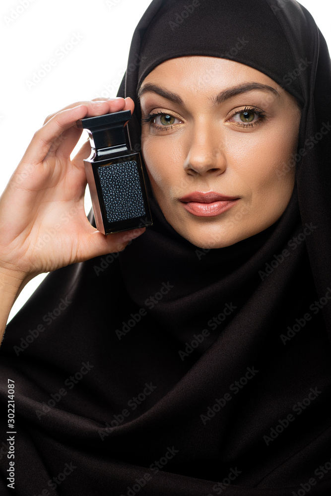 young Muslim woman in hijab holding bottle of perfume isolated on white young Muslim woman in hijab holding bottle of perfume isolated on white