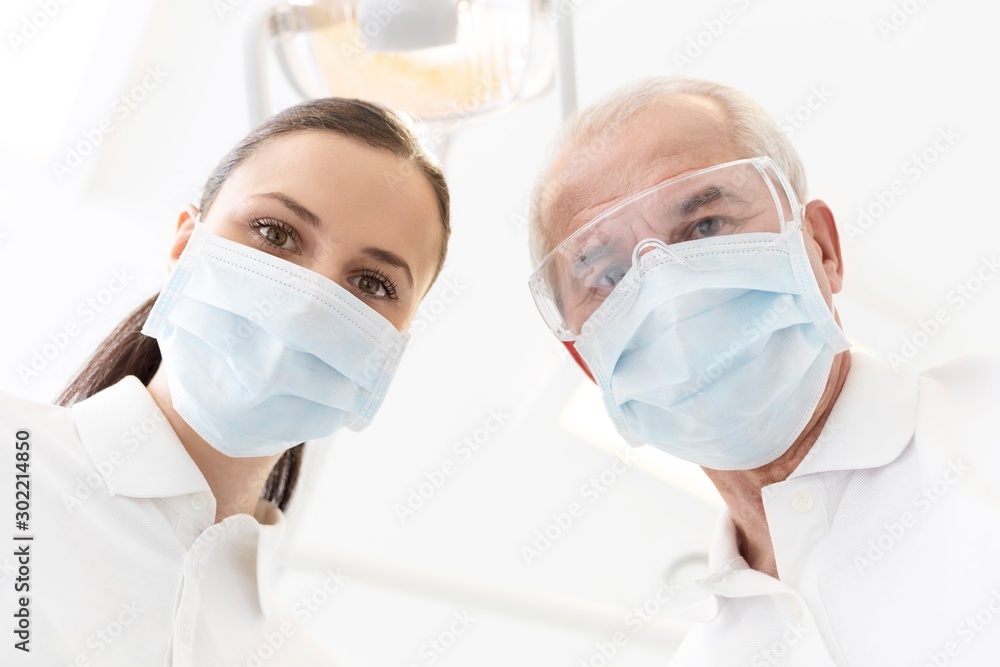 Doctor with assistant cleaning or pulling patient teeth in clinic