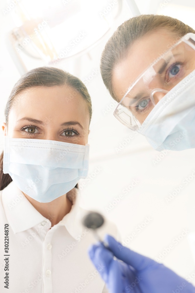 Doctor with assistant cleaning or pulling patient teeth in clinic Doctor with assistant cleaning or pulling patient teeth in clinic