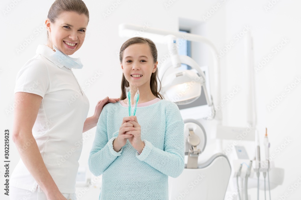 Child patient holding toothbrush with dentist in clinic Child patient holding toothbrush with dentist in clinic