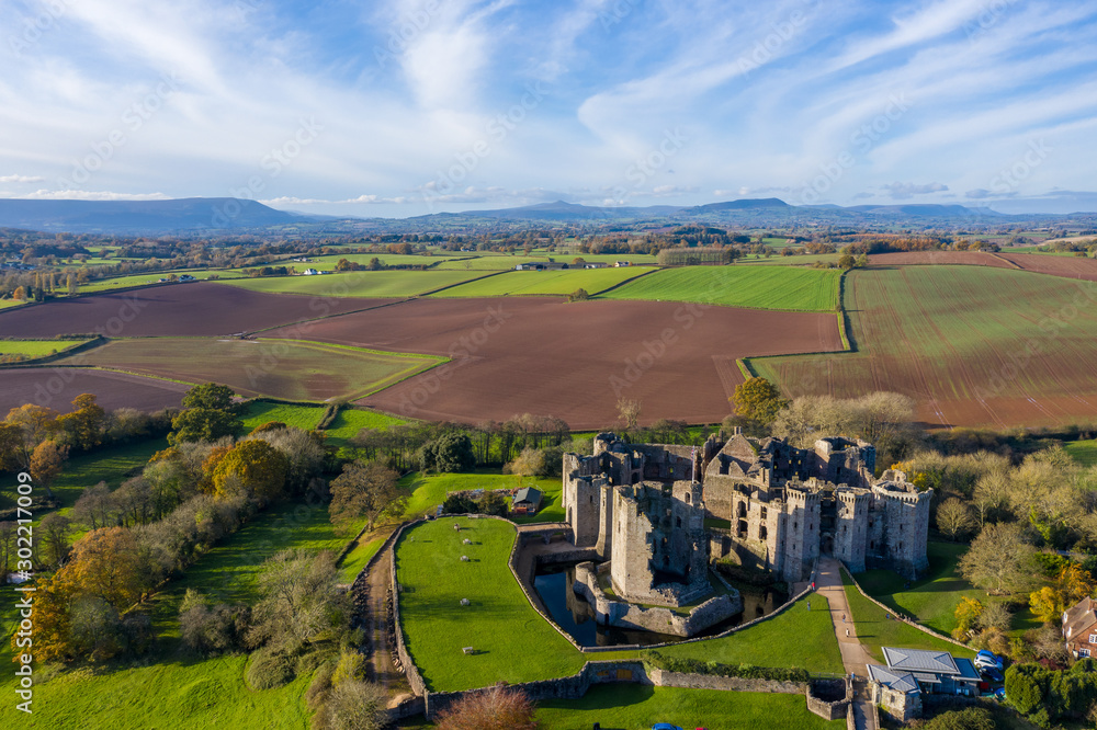 Aerial view of a large medieval castle showing the turrets, walls and moat (Raglan Castle, South Wales)
