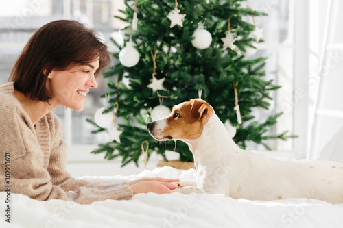 Tableau sur toile Horizontal shot of beautiful cheerful woman enjoys togetherness with dog, holds