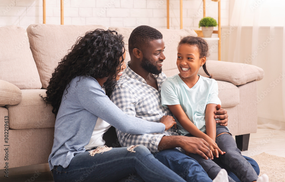 Black parents and daughter laughing, spending time together at home. Black parents and daughter laughing, spending time together at home.