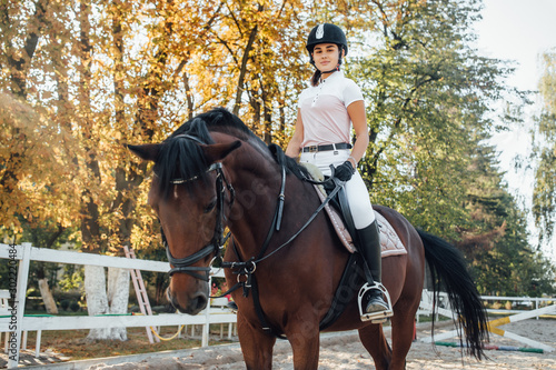 Young gorgeous woman in special uniform and helmet riding horse. Equestrian sport, dressage.