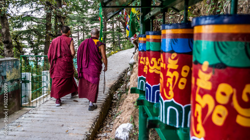 Tibetan Monks walking among praying wheels, Dharamsala, India photo