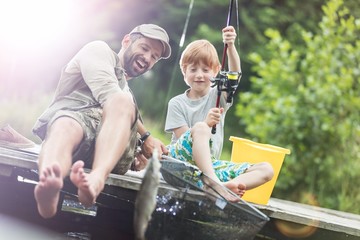 Full length of smiling father and son catching fish in butterfly fishing net