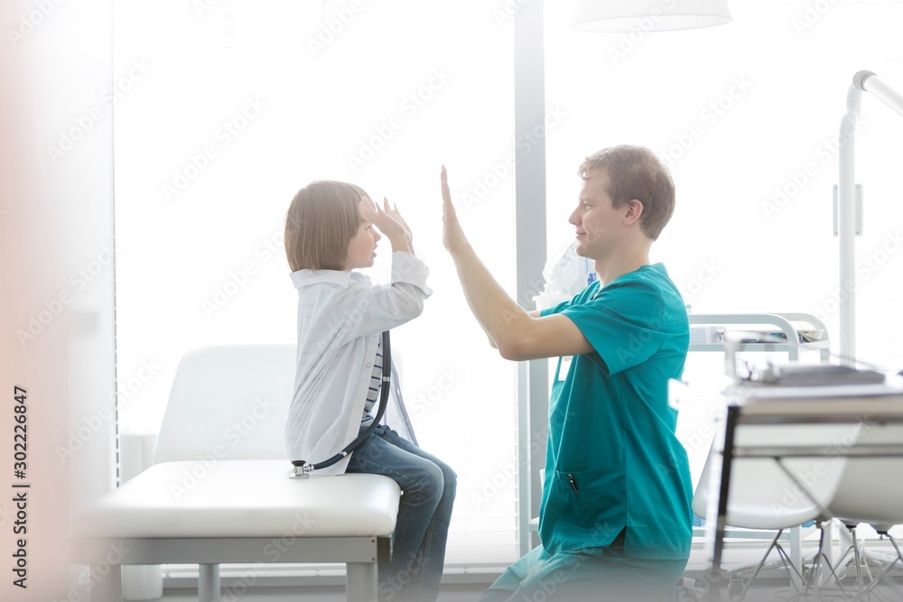 Nurse giving child patient high five in clinic