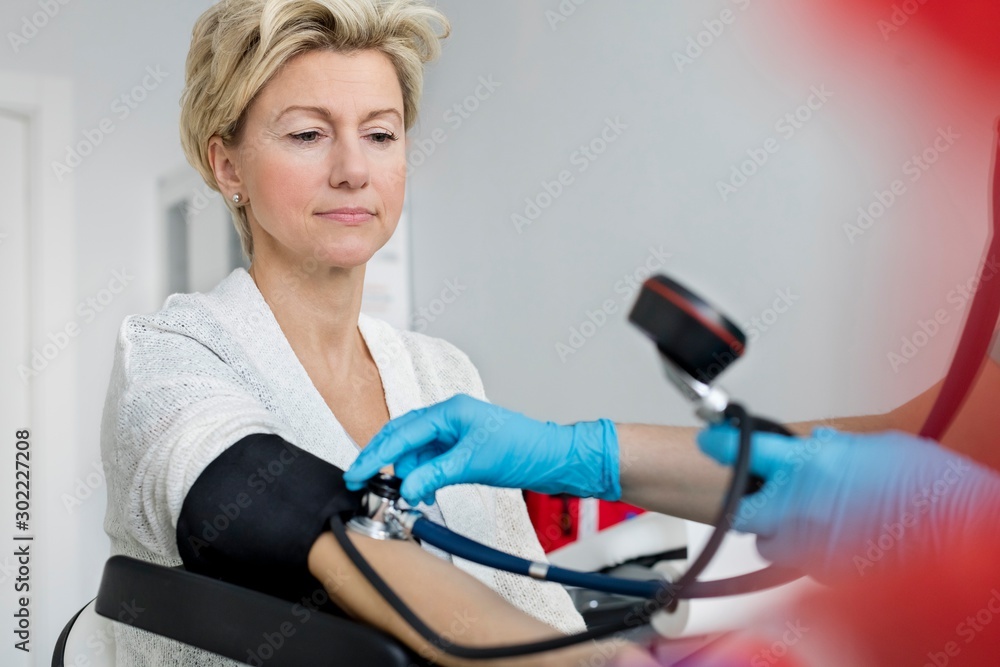 Nurse checking blood pressure of senior woman patient in clinic Nurse checking blood pressure of senior woman patient in clinic