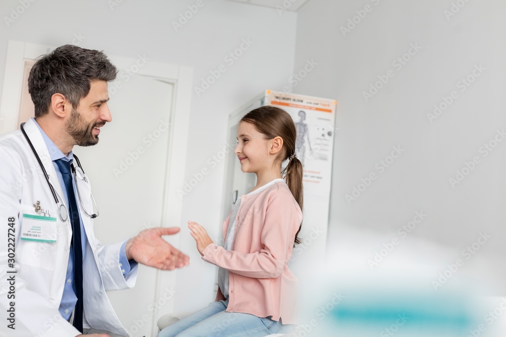 Pediatrician giving child patient high five in clinic