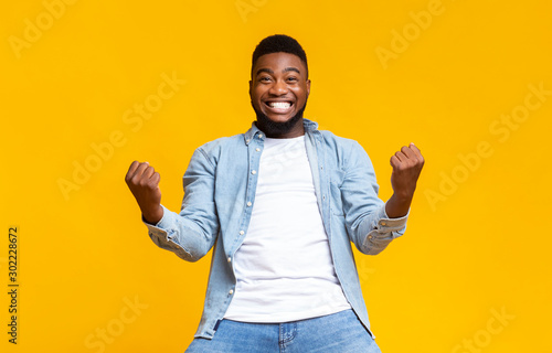 Portrait of overjoyed black man celebrating success with clenched fists