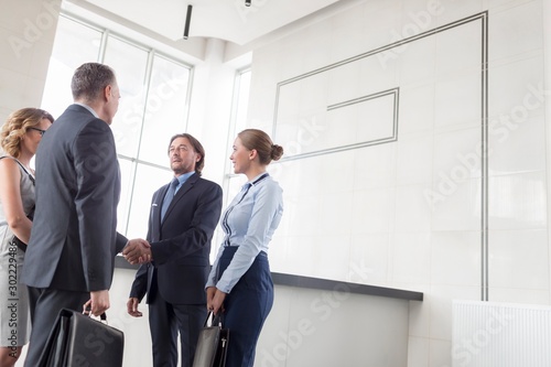 Business partners shaking hands with their secretary in office lobby © moodboard