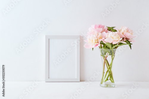 Mockup with a white frame and pink peonies in a vase on a white background