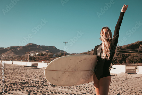 Canvas Print young woman standing with surfboard at Malibu beach