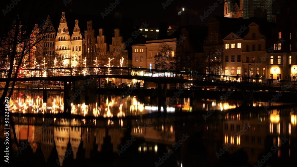 Lübeck at night with view over the Trave river with festive Christmas lighting in winter