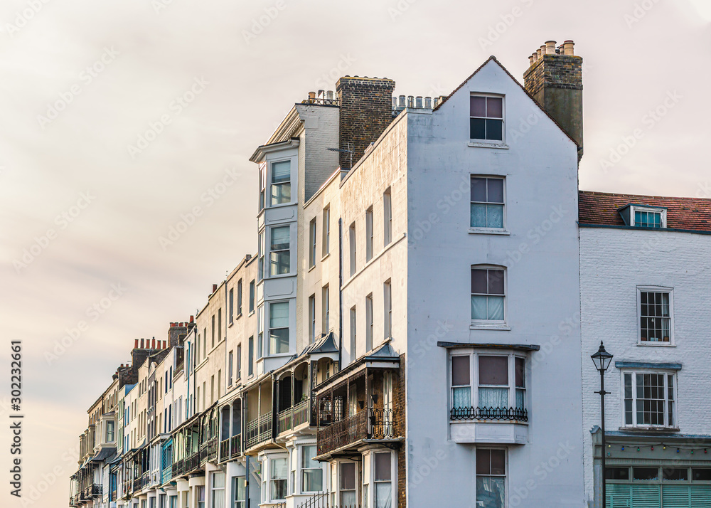Elegant white Victorian terrace houses with ornate balconies and white rendering catching glow of the late afternoon winter sun.
