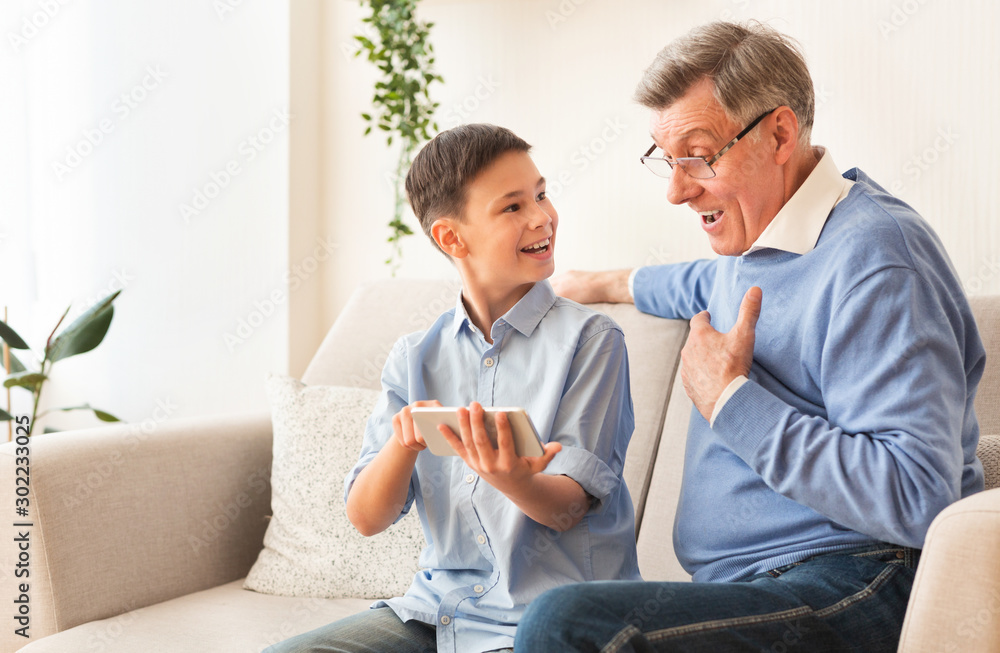 Boy Showing Grandfather How To Play On Smartphone Sitting Indoor Boy Showing Grandfather How To Play On Smartphone Sitting Indoor