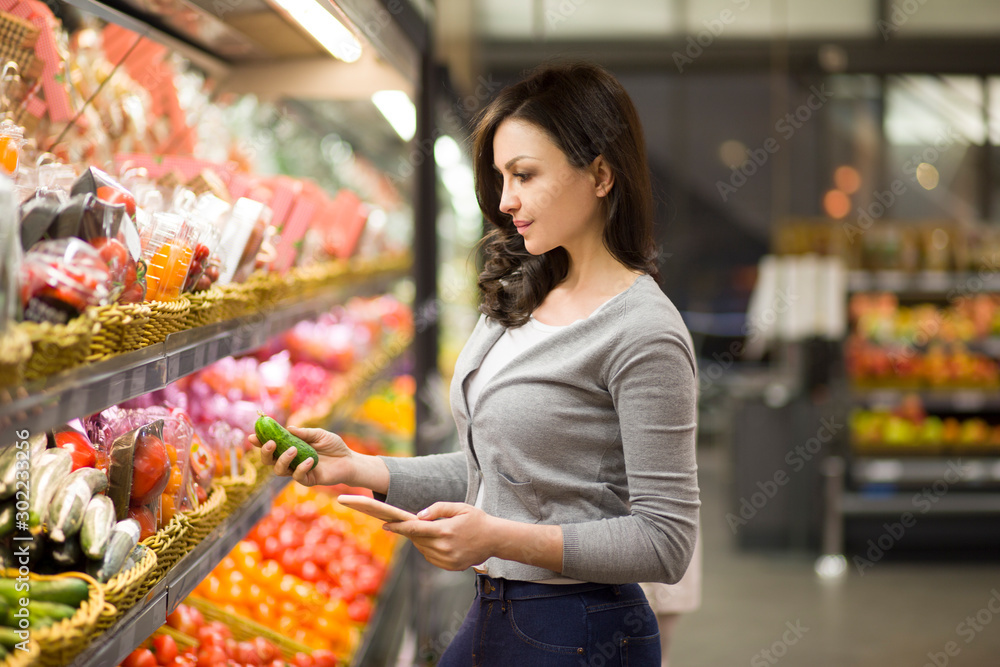 Woman choosing a dairy products at supermarket. Reading product information. Concept of information eating products, organic fruit and vegetables