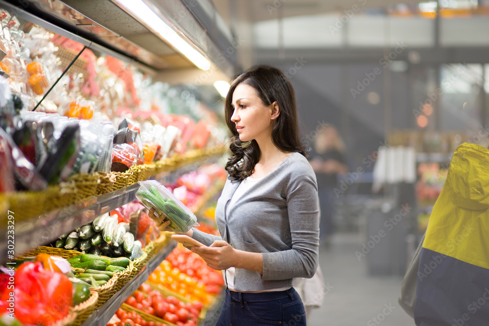 Woman choosing a dairy products at supermarket. Reading product information. Concept of information eating products, organic fruit and vegetables