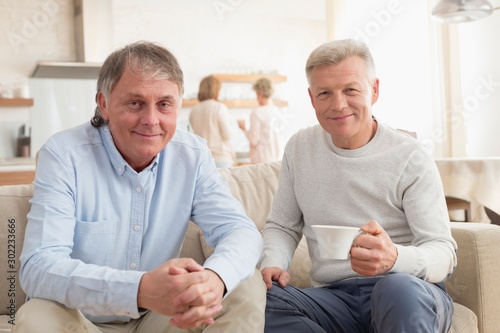 Portrait of smiling mature men sitting on sofa at home