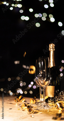 Wallpaper Mural New Year's Eve background with champagne bottle and glasses confetti and gold snakes New Year's Eve background with confetti and gold snakes on wooden table, lights Torontodigital.ca