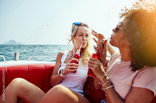 Smiling friends sitting on a boat together enjoying drinks