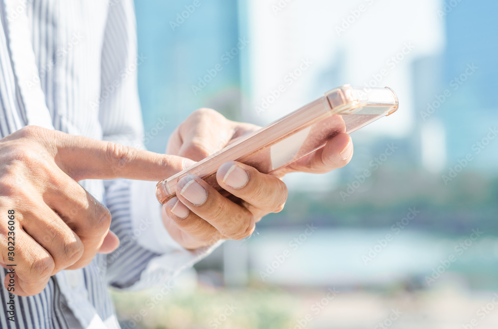 close up handsome man using hand typing smartphones and touch screen working search with app devices outdoor in city with sunrise and building background. 5G technology connecting the world. close up handsome man using hand typing smartphones and touch screen working search with app devices outdoor in city with sunrise and building background. 5G technology connecting the world.