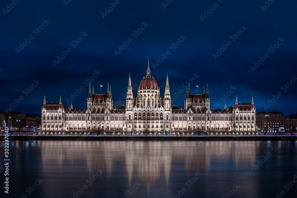 Budapest, Hungary - Illuminated Hungarian Parliament building with blue cloudy sky and reflection on River Danube at dusk