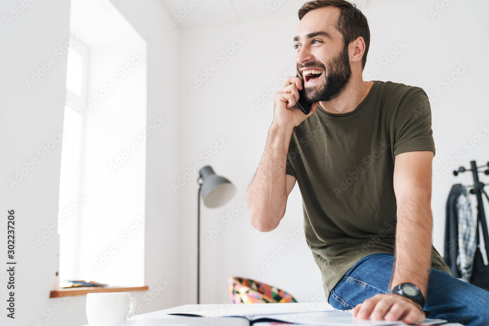 Image of laughing man talking on cellphone and reading documents Image of laughing man talking on cellphone and reading documents
