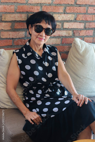 Asian senior woman sitting on couch and smiling
