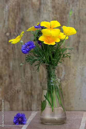 Goldmohn und Kornblumen in Glasvase photo