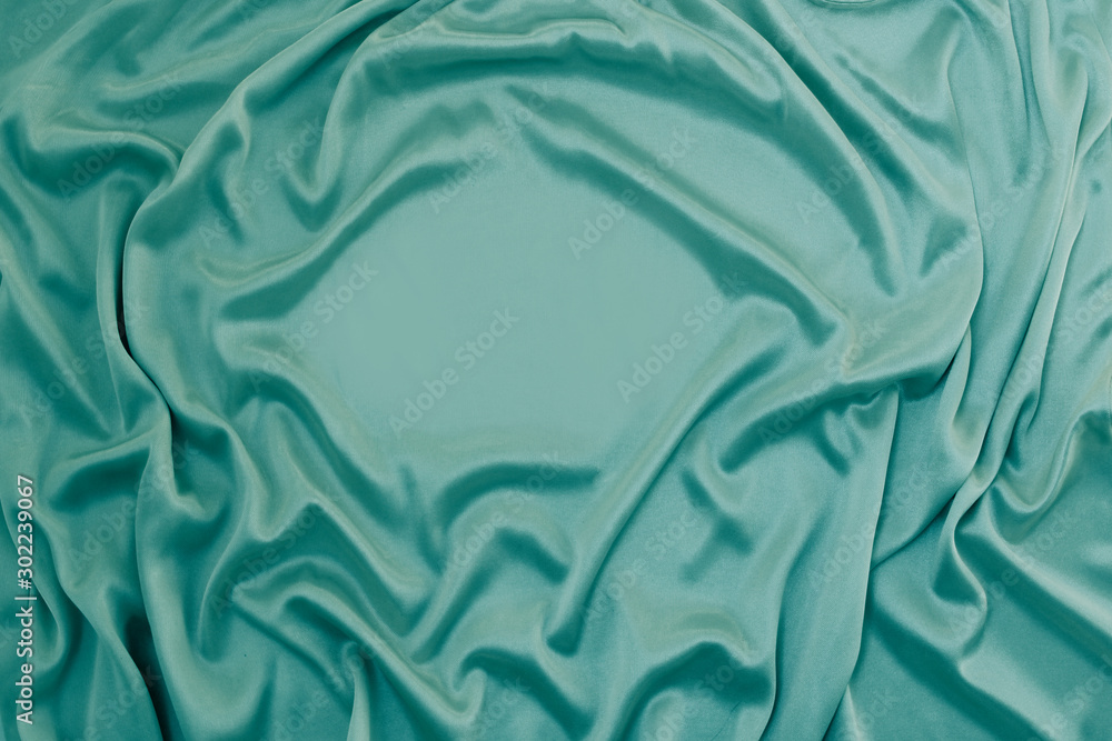 Obraz premium Photograph of silk fabric, color green. The texture of silk fabric. Luxury silk fabric background with waves and drapery. Background for fashion luxury design, close-up, copy space