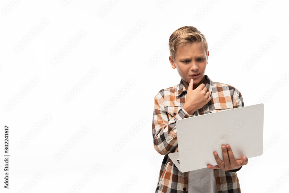 thoughtful boy looking at laptop and holding hand near face isolated on white thoughtful boy looking at laptop and holding hand near face isolated on white