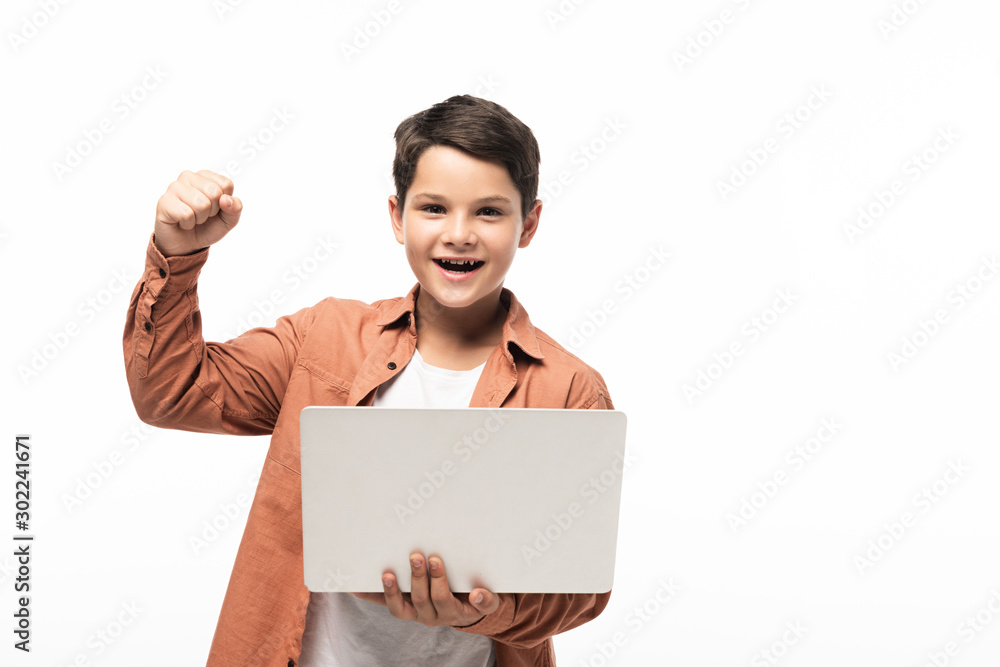 cheerful boy holding laptop and showing winner gesture isolated on white cheerful boy holding laptop and showing winner gesture isolated on white