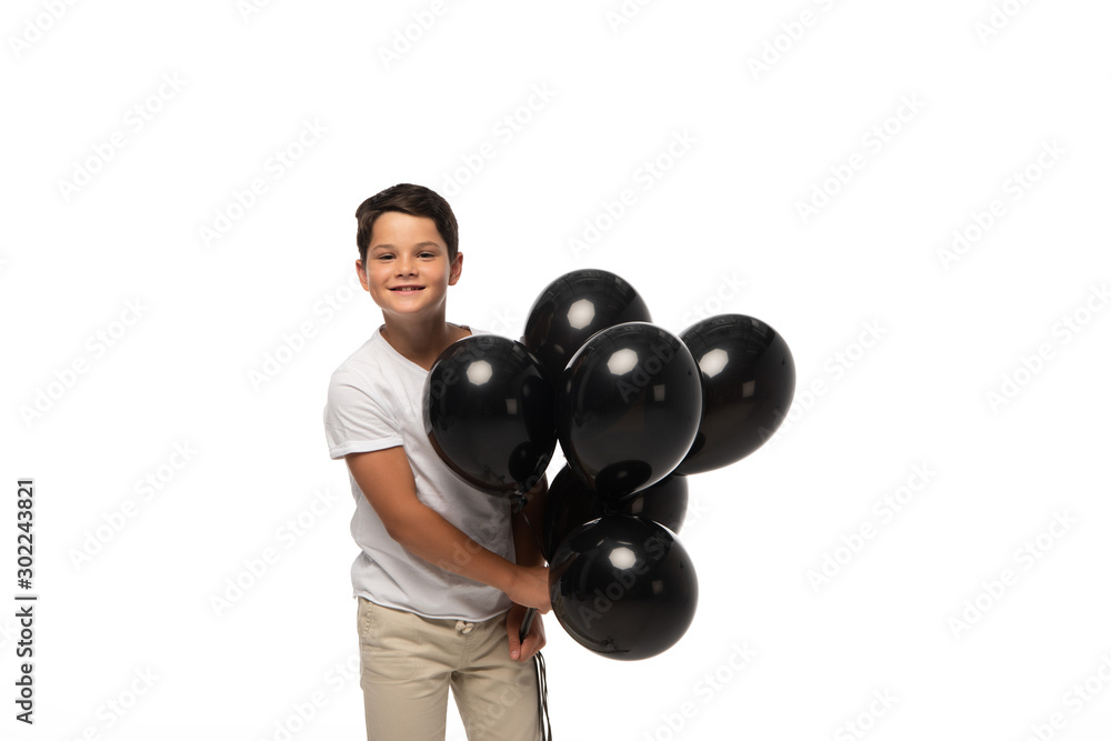 happy boy looking at camera while holding black balloons isolated on white happy boy looking at camera while holding black balloons isolated on white