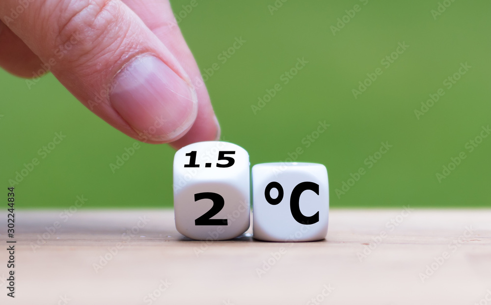 Symbol for limiting global warming. Hand turns a dice and changes the expression "2°C" to "1.5°C", or vice versa. - obrazy, fototapety, plakaty 