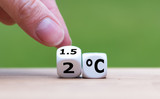 Symbol for limiting global warming. Hand turns a dice and changes the expression 