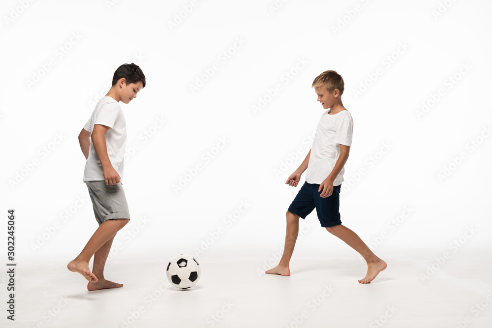 two brothers in pajamas playing football on white background