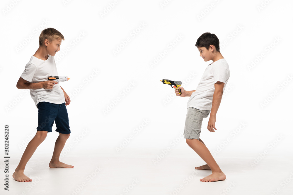 Naklejka premium two brothers aiming at each other with toy guns on white background