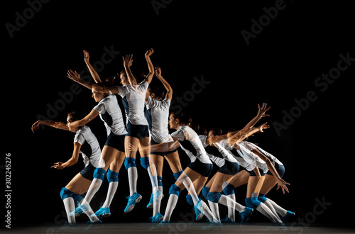 Young female volleyball player isolated on black studio background. Woman in sport's equipment and shoes or sneakers training and practicing. Concept of sport, healthy lifestyle, motion and movement.