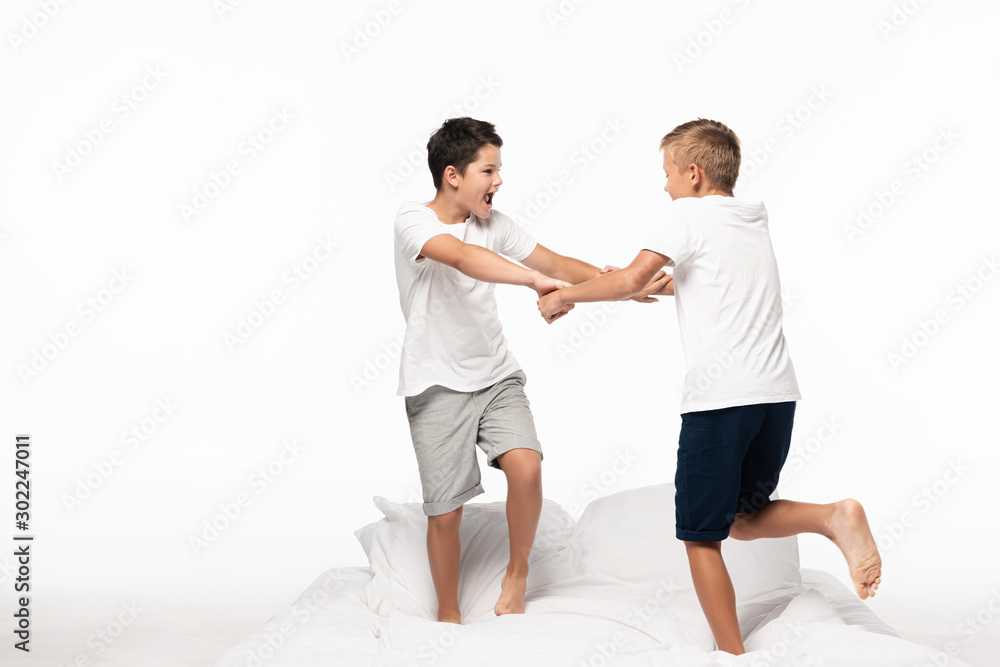 two brothers fighting for fun white standing on bed isolated on white two brothers fighting for fun white standing on bed isolated on white