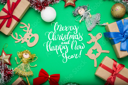 Christmas decorations, Christmas toys and gift boxes on a green background. Added text Merry Christmas and Happy New Year. Flat lay, top view