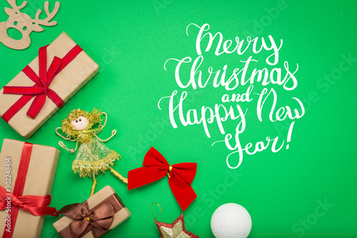 Christmas decorations  Christmas toys and gift boxes on a green background. Added text Merry Christmas and Happy New Year. Flat lay  top view