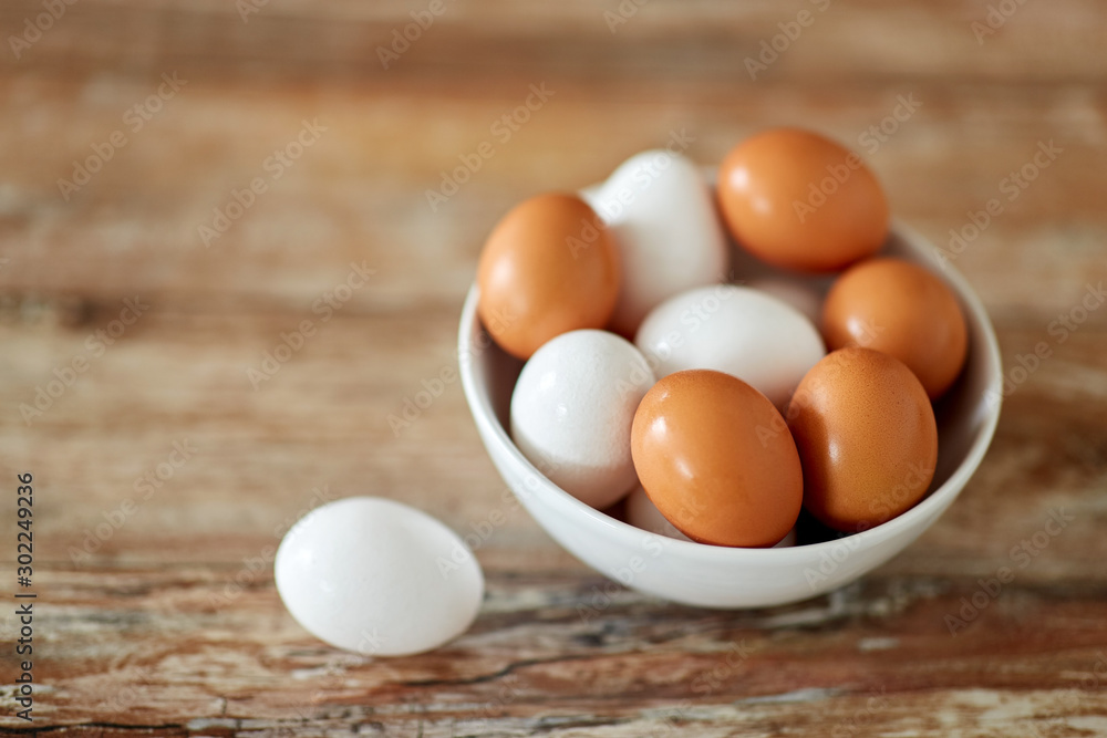 food, culinary and cooking concept - close up of natural chicken eggs in ceramic bowl on wooden table food, culinary and cooking concept - close up of natural chicken eggs in ceramic bowl on wooden table