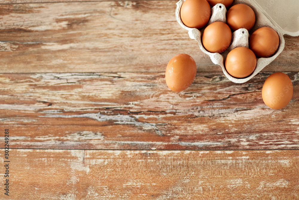 food, culinary and cooking concept - close up of natural chicken eggs in cardboard box on wooden table food, culinary and cooking concept - close up of natural chicken eggs in cardboard box on wooden table