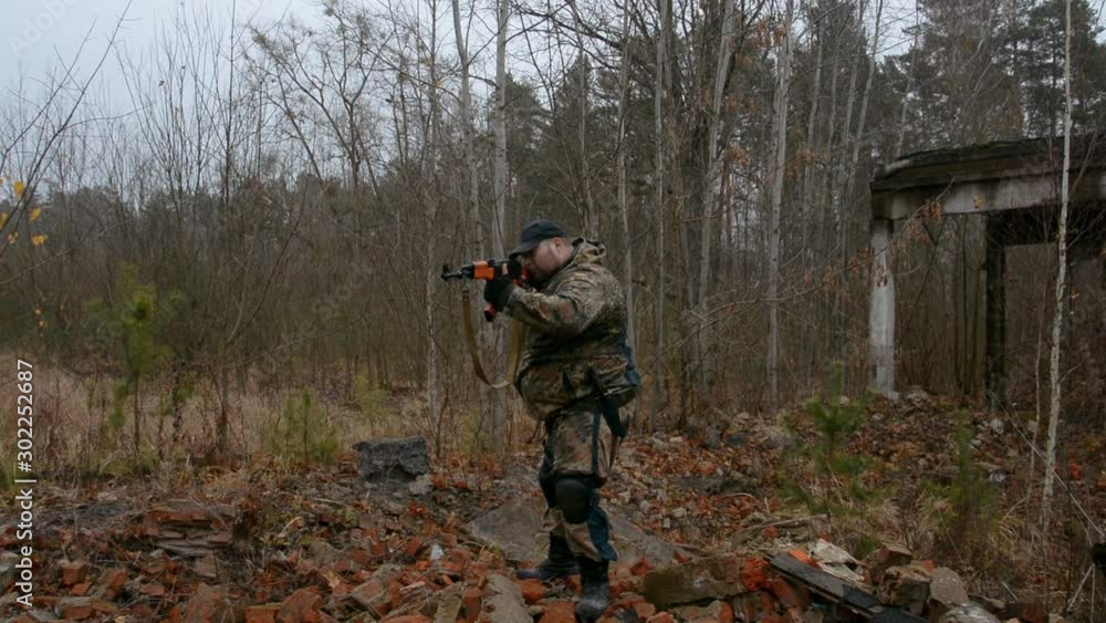 Unrecognizable soldier lying in forest and aiming with assault rifle, military concept Unrecognizable soldier lying in forest and aiming with assault rifle, military concept