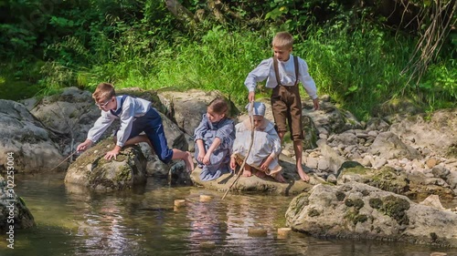 Kids are dressed in old-fashioned clothes and they're playing with tree branches and water.