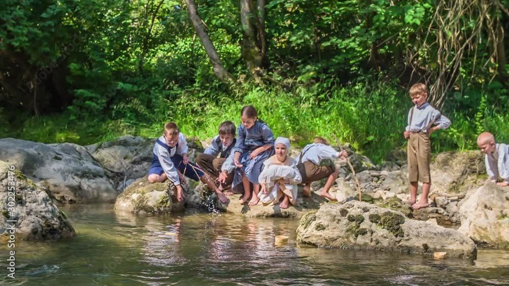 Beautiful children dressed in old-fashioned clothes are playing the water and it seems they're enjoying themselves. Beautiful children dressed in old-fashioned clothes are playing the water and it seems they're enjoying themselves.